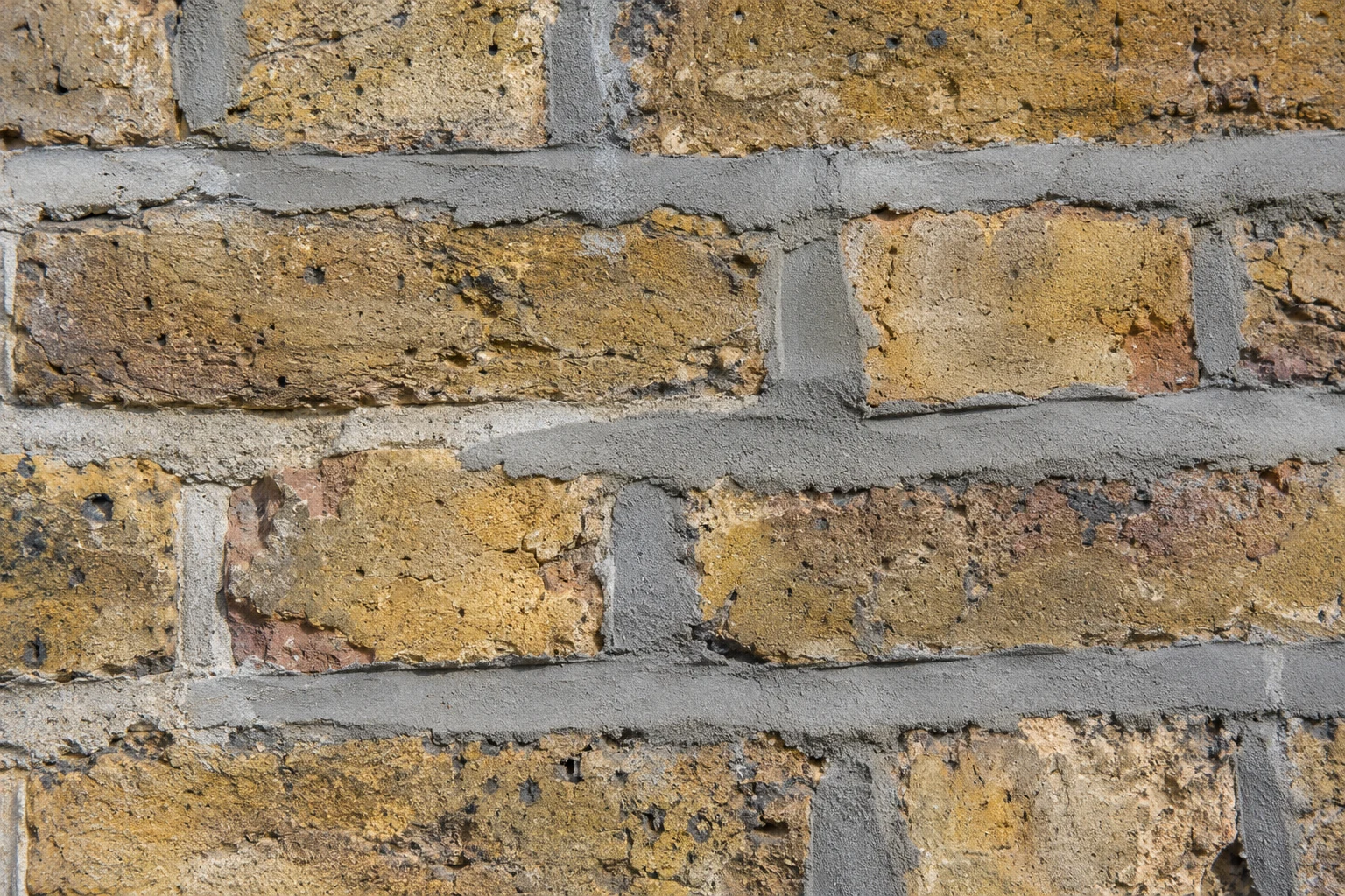 Close-up of weathered period brickwork with grey cement repointing